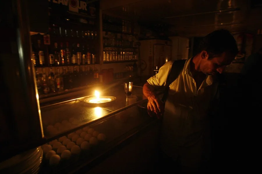 Un cliente asiste a un bar a oscuras en Río de Janeiro por un corte de energía. EFE/Antonio Lacerda
