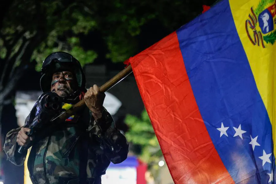 Un integrante de la FANB sosteniendo una bandera venezolana durante una marcha popular. (Xinhua/Str) 