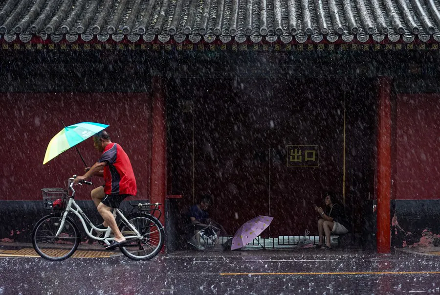 Un hombre monta en bicicleta en medio de la lluvia, en Beijing, capital de China, el 30 de julio de 2023. (Xinhua/Chen Zhonghao)