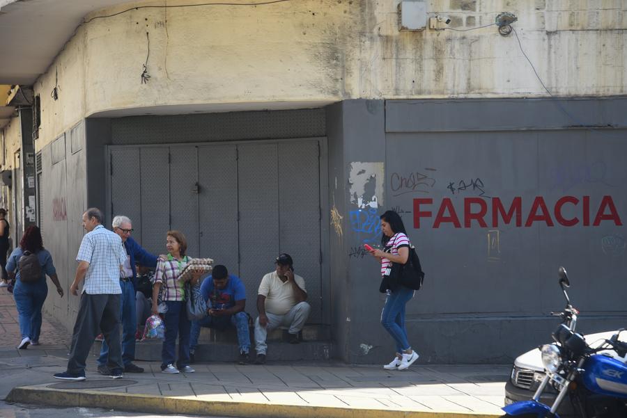 Personas caminan frente a comercios cerrados durante un apagón eléctrico, en Caracas, Venezuela, el 30 de agosto de 2024