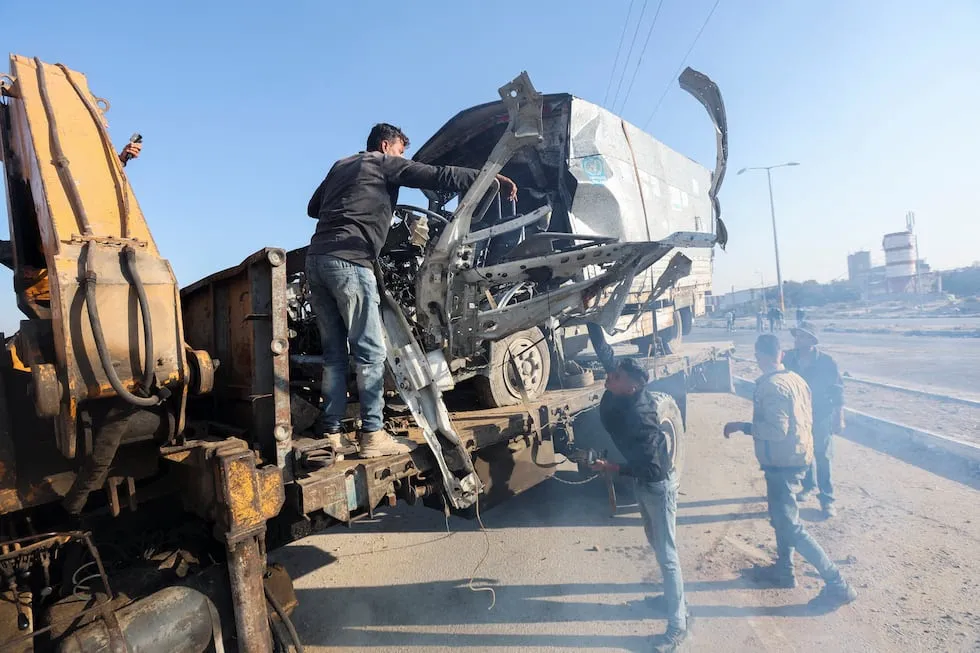 Hombres retiran un camión de la UNRWA destrozado por un bombardeo israelí