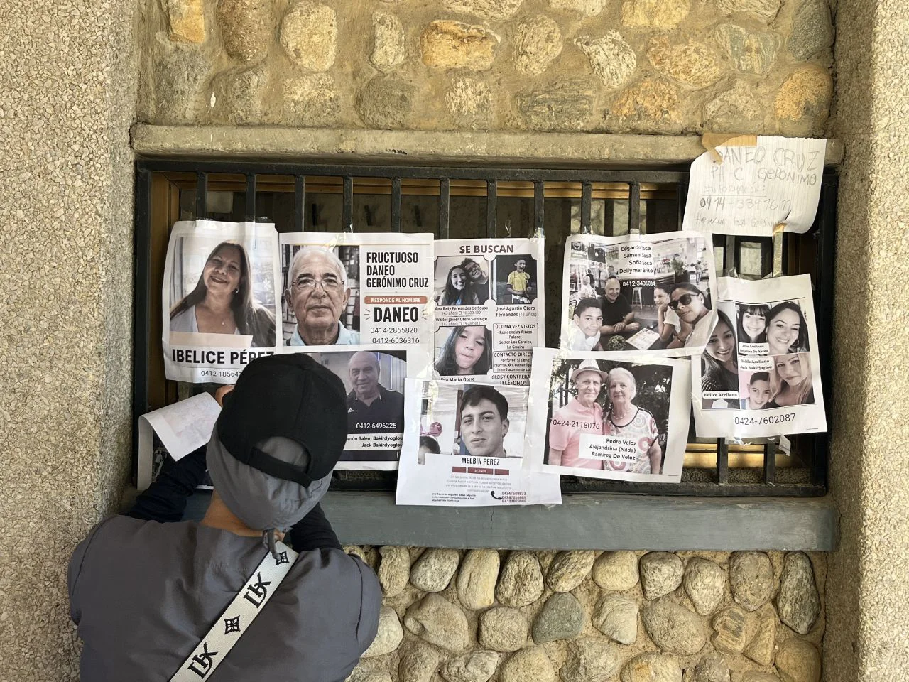 Persona coloca carteles de desaparecidos en un edificio colapsado en La Guaira. Foto: José Mireles Alcalá / ElMartilloVen.